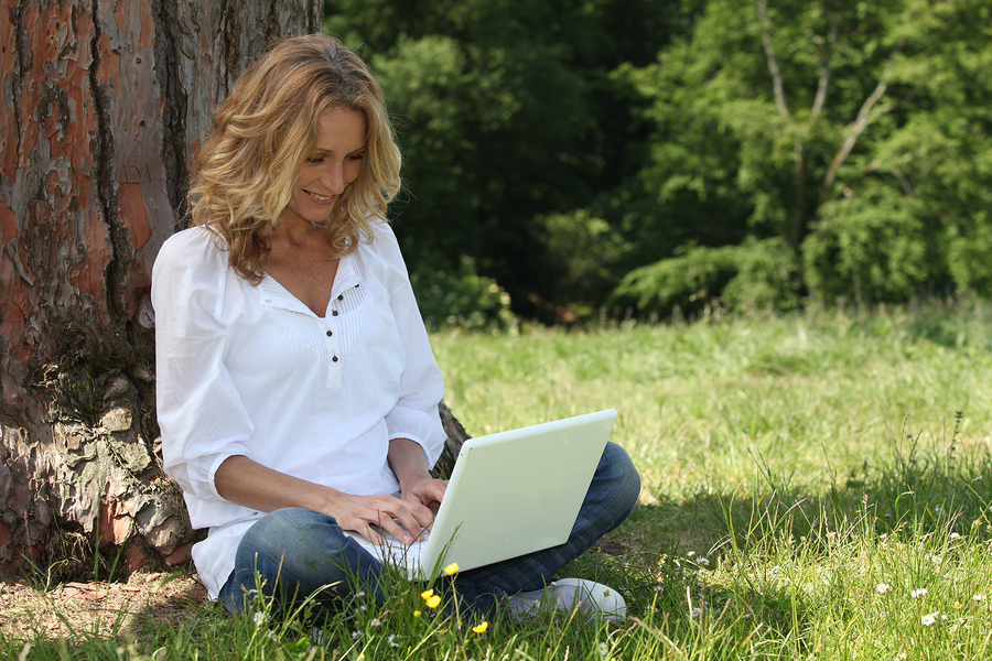 Woman laughing at her laptop computer in the park